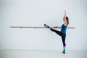 Dancer stretching on a barre while practicing dance