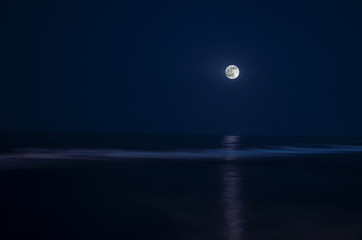 Full moon in night sky over moonlit water