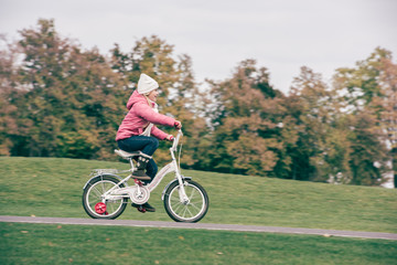 Naklejka premium Little girl riding bicycle in park
