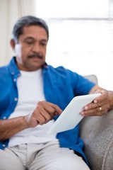 Senior man using digital tablet in living room