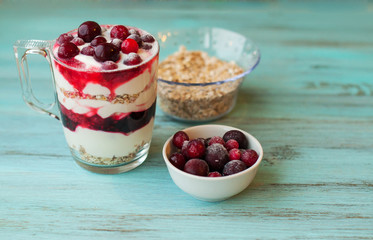 smoothie with berries, strawberries, raspberries, strawberries with yogurt and muesli on turquoise, wooden background.