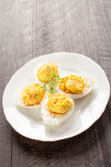 Small plate of four deviled eggs on dark wooden background