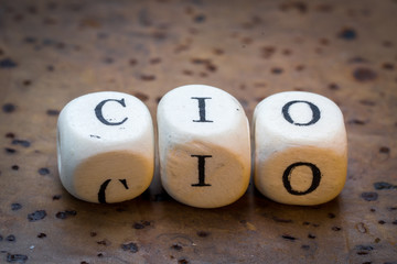 CIO (Chief Information Officer) text on wooden cubes on a brown cork background