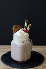 Vertical photo of big portion of hot chocolate with whipped cream, wafer sticks and heart-shaped caramel. Romantic breakfast. Valentine Day. Love concept