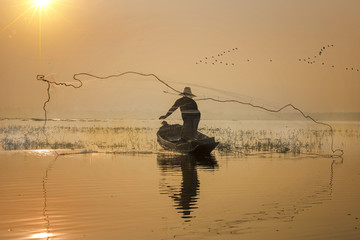 fisherman acting in throwing a net catching fish in lake morning scenery view