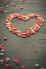 Heart made with small candy hearts, pink, red, whie colors, on dark background. Love, Valentine's day concept. Top view, copy space.