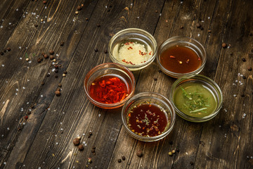 Sauces in glass bowls on wooden dark background