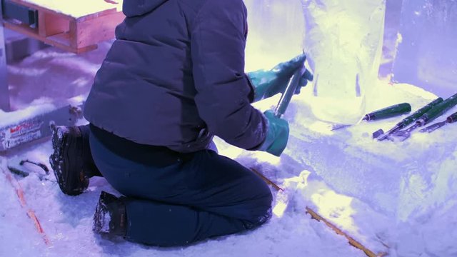 Man carves ice sculpture on knees