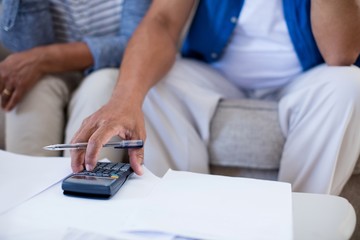 Senior couple checking bills in living room at home
