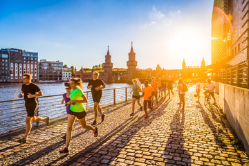 Groep vrouwelijke en mannelijke hardlopers joggen in stedelijk gebied bij zonsondergang