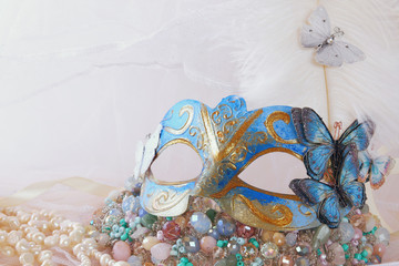 delicate blue venetian mask next to pearls and jewel