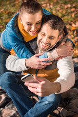 Fototapeta premium Beautiful smiling couple looking at smartphone