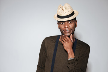 Handsome young african man wearing hat standing in studio
