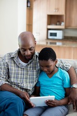 Father and son using digital tablet in living room