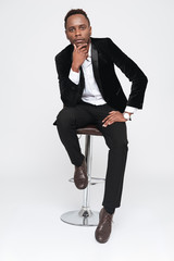Young african businessman sitting on stool.
