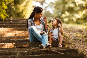 Fototapeta premium Mother and daughter relaxing in park.She reading a fairytale to her daughter