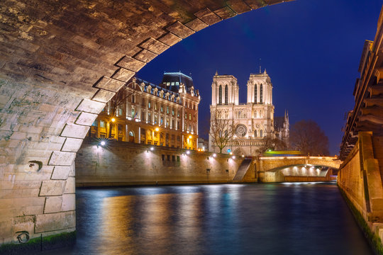 Fototapeta Cathedral of Notre Dame, Petit Pont and riverside of Seine river in Paris at night, France