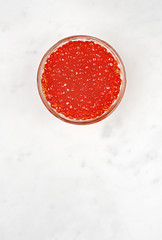 Bowl with red caviar on a marble table