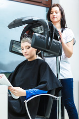 Woman in hairdresser, drying hair under machine