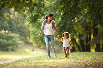 Fototapeta premium Mother and daughter playing and running around the park on beautiful morning.