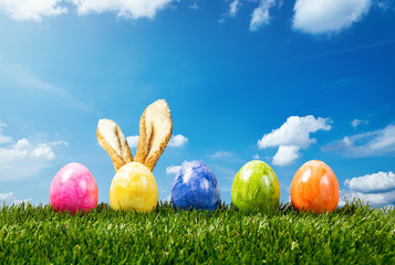 Ostereier mit Hasen Ohren in einer Reihe stehen auf einer Wiese