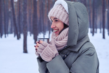 Smiley woman with a cup of coffee in a cold weather