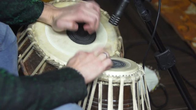 Close-up of man playing the tabla drum. A young man plays his djembe drum. Closeup man's hands drumming out beat on skin-covered bongo hand drum