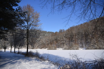 Blauer Winterhimmel über zugefrorenem See
