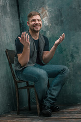 Portrait of smiling happy man sitting on the chair in studio