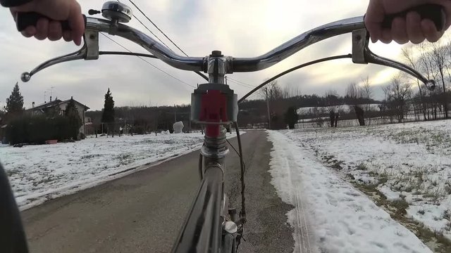 Point-of-view video of person riding a bicycle in the city in snowy winter day.