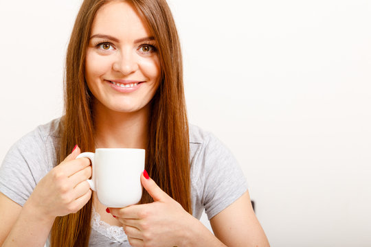 Smiling young woman holding cup of tea
