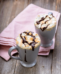S'mores drink. Two mugs of hot chocolate with marshmallows on a wooden table. Cocoa.