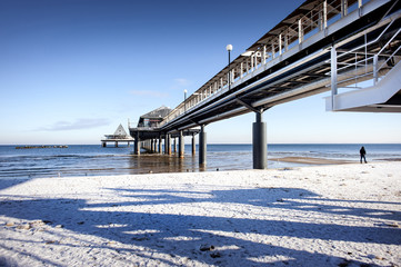 Germany, Usedom, Heringsdorf, Imperial Spa (Kaiserbad): Winter scene - snowy beach with sea bridge and pier. With 508 meters, it is the longest German seabridge. - obrazy, fototapety, plakaty