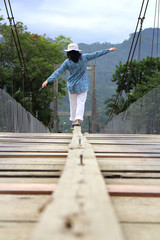 A lady on a wooden bridge with open arms. 