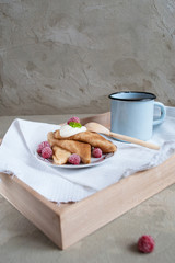 beautiful russian pancakes with sour cream, raspberry and vintage cup of tea on concrete background