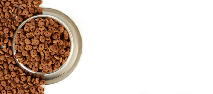 Cat bowl with pet feed on the half white background and scattered dry food