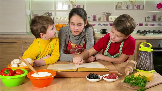 Three kids reading the cook book, making the dinner
