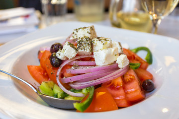 Greek salad with fresh vegetables, feta cheese and black olives, served on a plate in the restaurant. Greece.