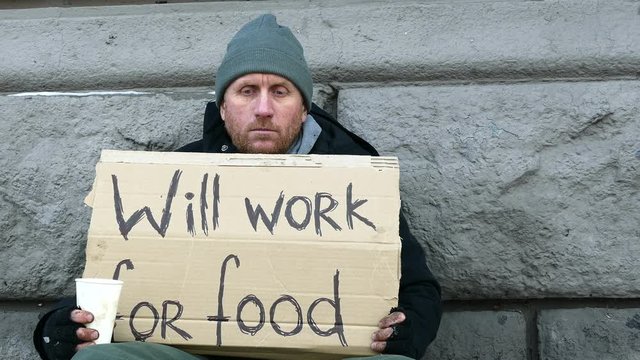 
4K. Adult  homeless  despair man looks for work on city street. Close up
