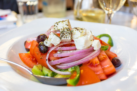 Greek salad with fresh vegetables, feta cheese and black olives, served on a plate in the restaurant. Greece.