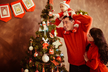The mother,father  and son decorating a Christmas tree