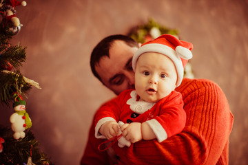 The father holds of hands his son near Christmas tree