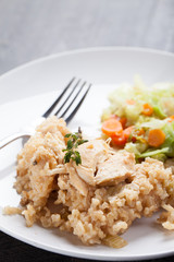 Lemon pepper chicken on brown rice with steamed carrots and cabbage on a dark wooden background vertical shot