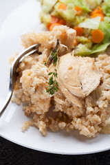 Lemon pepper chicken on brown rice with steamed carrots and cabbage on a dark wooden background close up of chicken