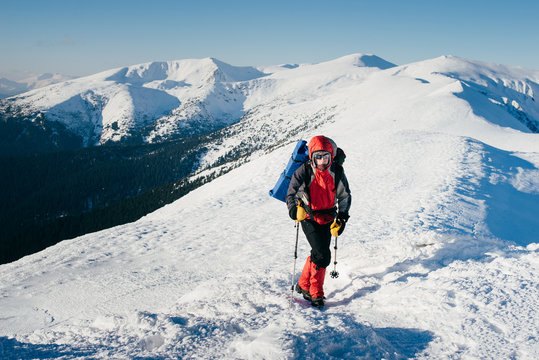 Man with backpack is hiking in snowy winter mountains