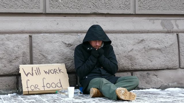 
4K.  Homeless  despair man  in  city winter  street considers cents . Unemployment  beggar symbol
