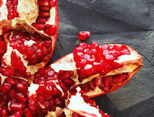 Red juicy pomegranate fruit , close up on a dark surface