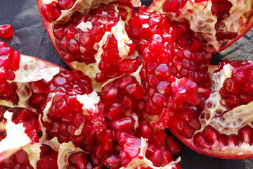 Red juicy pomegranate fruit , close up on a dark surface