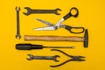 Set of old rusty tools on a yellow background, with space for text