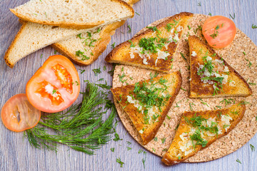 Гренки с чесноком и укропом, помидор на деревянном столе